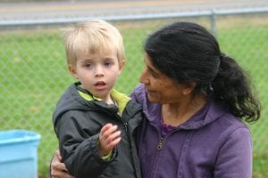 Teacher holds child outside on playground