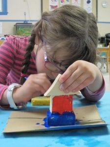 Girl paints a small wooden sculpture