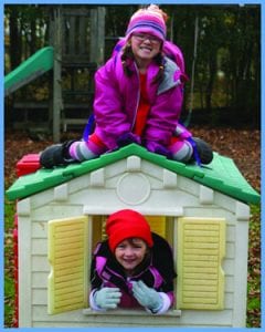 Two children play outside in a playhouse